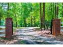 Elegant driveway gate with brick columns and decorative ironwork, set amidst a serene, wooded landscape at 301 East Highway 5, Roopville, GA 30170