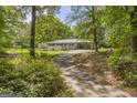 Long driveway leading to a bright home surrounded by lush greenery and mature trees on a sunny day at 2164 Old Rex Morrow Rd, Morrow, GA 30260