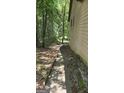 Image features the side of the house and the surrounding wooded land at 1448 Se Hillside Place, Conyers, GA 30094