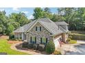 Exterior view of this beautiful home showcasing the stone facade, attached garage, and well-maintained yard at 320 Silverbell Ln, Sharpsburg, GA 30277