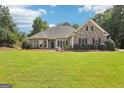 Beautiful single-story house with a lush green lawn, stone accents, and dark window shutters at 320 Silverbell Ln, Sharpsburg, GA 30277
