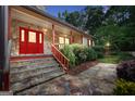 Welcoming front entrance featuring a red door, stone steps, and a charming stone walkway, all surrounded by lush greenery at 123 Eva Ln, Stockbridge, GA 30281