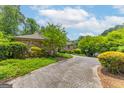 Long driveway leading to a brick and stone home with lush landscaping at 1919 Lake Lucerne Sw Way, Lilburn, GA 30047