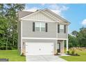 View of a two-story home with gray siding and a two-car garage, set against a backdrop of trees at 282 Limestone Circle, Conyers, GA 30013