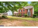 A view of the front of the brick home surrounded by mature trees and landscaping at 10044 Point View Dr, Jonesboro, GA 30238