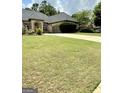 Beautiful brick home features a well-manicured lawn and a spacious driveway leading to an attached two-car garage at 6409 Caledon Ct, Locust Grove, GA 30248