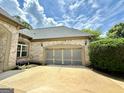 A view of the brick-faced home's large two-car garage with frosted windows at 6409 Caledon Ct, Locust Grove, GA 30248