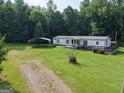 A white single-story home with a metal roof, a spacious yard, and a convenient carport at 323 Hollonville Rd, Brooks, GA 30205