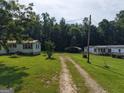 Two single-story homes with carports are nestled in a vast yard surrounded by lush trees at 323 Hollonville Rd, Brooks, GA 30205