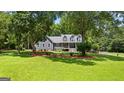 A well-manicured lawn complements this charming gray home, nestled amongst mature shade trees at 152 Bear Creek Rd, Moreland, GA 30259