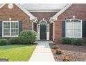 Inviting red brick home with a black front door and manicured bushes and flowers at 1032 Shumard Ln, Mcdonough, GA 30252
