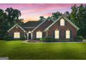 Charming single-story red brick home with manicured lawn at sunset at 1032 Shumard Ln, Mcdonough, GA 30252