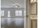 Spacious living room with wood-look floors, ceiling fan, and natural light is adjacent to a half bathroom at 4454 Eastbrook Pl # 57B, Snellville, GA 30039