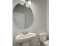 Powder room featuring a pedestal sink, round mirror, and a toilet at 4434 Eastbrook Pl # 59A, Snellville, GA 30039