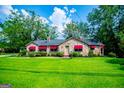 Charming stone home with bright green lawn, red awnings, and mature trees creates inviting atmosphere at 508 College St, Bowdon, GA 30108