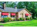 Charming stone home with red awnings and well-manicured landscaping creates a welcoming entrance at 508 College St, Bowdon, GA 30108