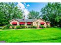 Charming stone home with bright green lawn, red awnings, and mature trees offers nice curb appeal at 508 College St, Bowdon, GA 30108