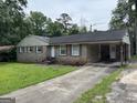 Quaint brick home with an attached carport and a driveway, surrounded by a green lawn at 3929 Rockey Valley Dr, Conley, GA 30288