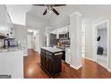 Well-lit kitchen with white cabinets, stainless steel appliances, island and hardwood floors at 1535 Smoke Hill Dr, Hoschton, GA 30548