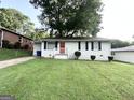 Classic white home featuring a well-kept lawn, brick accents, and a welcoming front porch at 70 Macon Se Pl, Atlanta, GA 30354