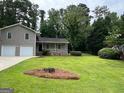 Charming two-story home with a well-manicured lawn, mature trees, and a stone accented porch at 7562 Asbury Manor, Lithonia, GA 30058