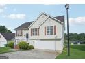 Well-maintained home with light siding, attached garage, landscaping, and red shutters that add a touch of color at 4738 Golod Way, Lithonia, GA 30038