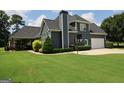 Back exterior with large windows, basketball hoop, well-maintained lawn, and covered patio with ceiling fans at 9 Warrior Way, Sharpsburg, GA 30277