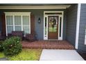 Inviting front porch with brick flooring, stylish seating, and a decorative wreath on the glass paneled front door at 9 Warrior Way, Sharpsburg, GA 30277