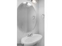 Clean half bathroom featuring pedestal sink, modern faucet, and round mirror at 505 Mariposa Ln, Mcdonough, GA 30253