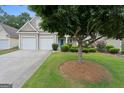 Charming home featuring a two-car garage and an inviting front yard with mature landscaping at 377 Avian Forest Dr, Stockbridge, GA 30281