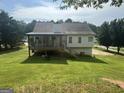 Expansive backyard featuring a covered porch, lush green grass, and mature trees, perfect for outdoor enjoyment at 51 Estates Dr, Villa Rica, GA 30180