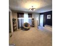Inviting living room featuring plush carpet, a unique swivel chair, neutral walls, and decorative shelving, showcasing ample space at 10178 Top Tree Ct, Jonesboro, GA 30238