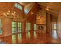 Spacious living room featuring a stone fireplace, wood-paneled walls, and cathedral ceilings at 1051 Lake Rutledge Rd, Rutledge, GA 30663