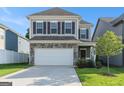 Two-story home featuring stone accents, a two-car garage, a green lawn, and neutral colored siding at 2384 Hastings Manor Ln, Hampton, GA 30228