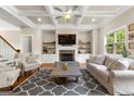 Spacious living room with coffered ceilings, built-in shelves, a stone fireplace, and modern furnishings at 195 Berry Hill Ln, Tyrone, GA 30290