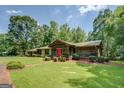 Ranch home featuring a red front door, manicured lawn, and mature trees at 2400 White Pine Ln, Mansfield, GA 30055