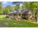 A beautiful single-Gathering home with lush green lawns, mature trees, and a charming covered front porch at 603 Lakewood Dr, Social Circle, GA 30025