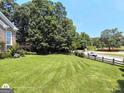 Expansive green backyard with a wooden fence, mature trees and a glimpse of a neighboring street at 1292 Hidden Spirit Trl, Lawrenceville, GA 30045