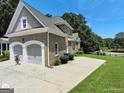 Side view of a brick house highlighting the two-car garage, driveway, and well-maintained landscaping at 1292 Hidden Spirit Trl, Lawrenceville, GA 30045