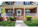 Inviting front porch with white columns, complemented by a brick facade and meticulous landscaping at 419 Tea Rose N Ln, Stockbridge, GA 30281