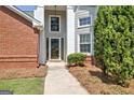 Close-up of the front door with sidelights and decorative glass, flanked by brick and greenery at 316 Kensington Dr, Peachtree City, GA 30269