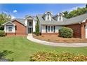 Attractive front exterior featuring brick accents, dormer windows, and a green lawn at 316 Kensington Dr, Peachtree City, GA 30269