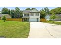 Two-story home with a spacious front yard and driveway, light blue front door and wood fence at 9477 Forest Knoll Dr, Jonesboro, GA 30238