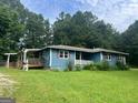Quaint single-story house with a side porch, surrounded by lush greenery and a spacious yard at 1041 Sandy Ridge Rd, Mcdonough, GA 30252