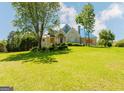 View of a two-story house with a large front lawn and boarded up windows and doors at 145 Windy Ridge Ct, Fayetteville, GA 30214
