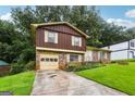 Split-level home featuring a brick and wood facade, attached garage, and concrete driveway at 1517 Indian Forest Trl, Stone Mountain, GA 30083