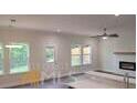 Sunlit living room boasts large windows, a ceiling fan, and fireplace at 4421 Meadowwood Dr, Loganville, GA 30052