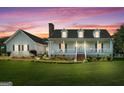 Inviting home exterior with a welcoming front porch, dormer windows, brick chimney and manicured lawn at sunset at 310 Trestle Rd, Locust Grove, GA 30248