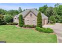 This brick home is surrounded by manicured landscaping, trees, and a well-kept lawn at 230 Hummingbird Ct, Hampton, GA 30228