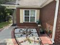 Charming brick home featuring a garden bed with flowers and a window with decorative shutters at 8113 Fieldstream Way, Douglasville, GA 30134
